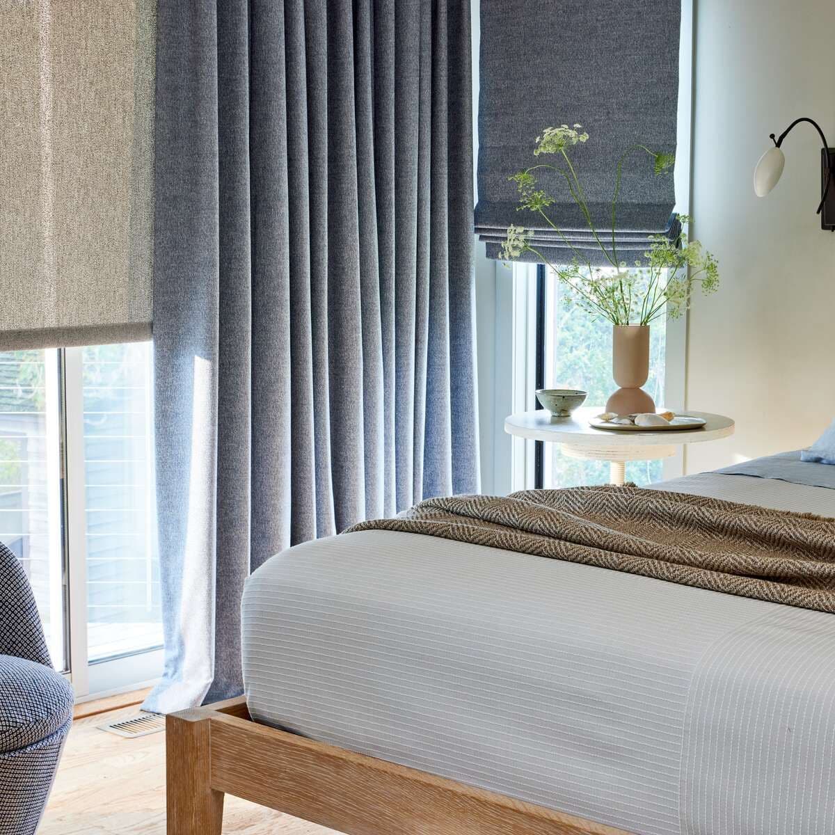 Drapery, solar shade and Roman shade in neutral blue and white bedroom Sunbrella